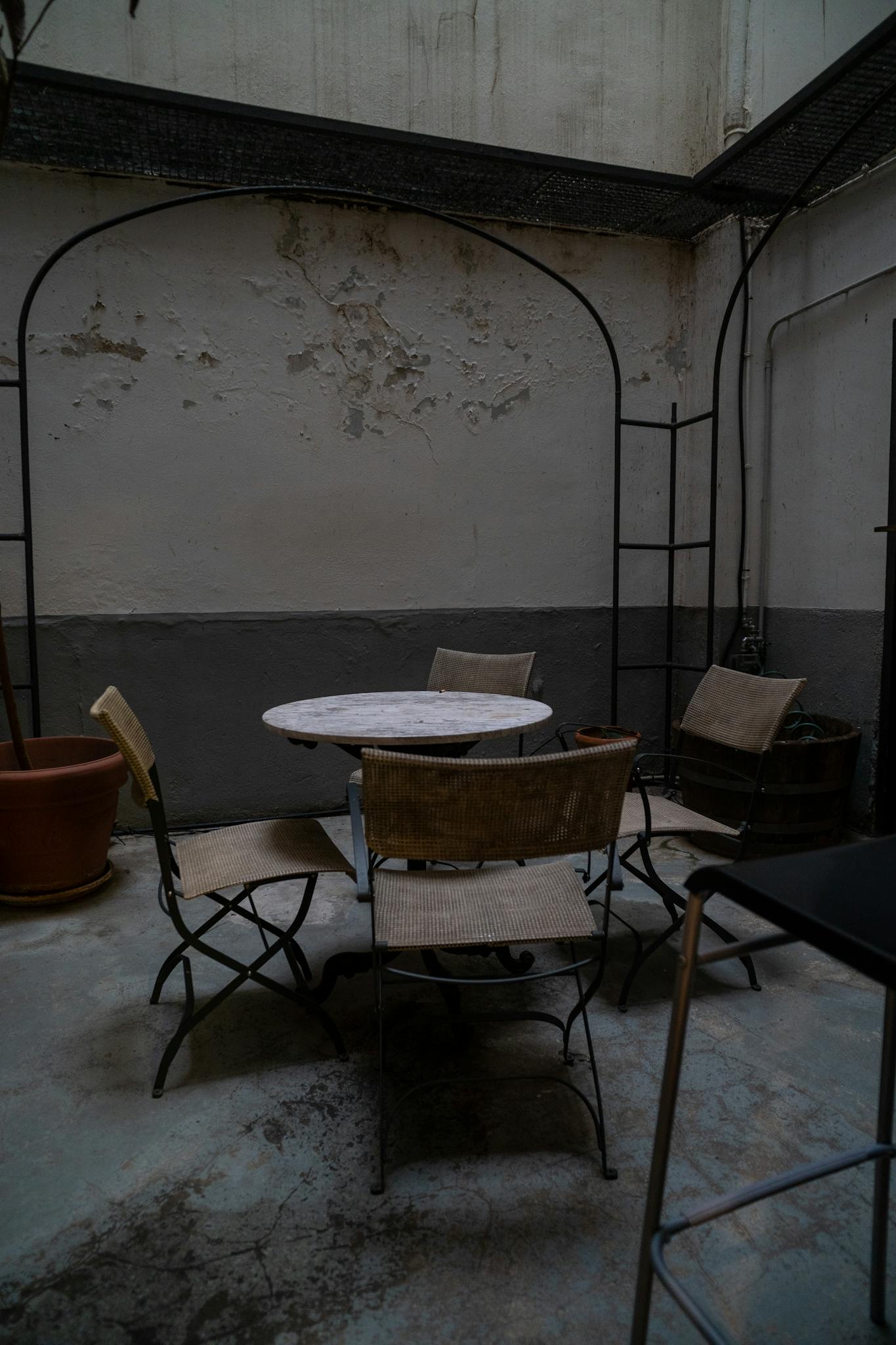 A rustic outdoor café patio with metal chairs and table in Madrid, showcasing a vintage ambiance.