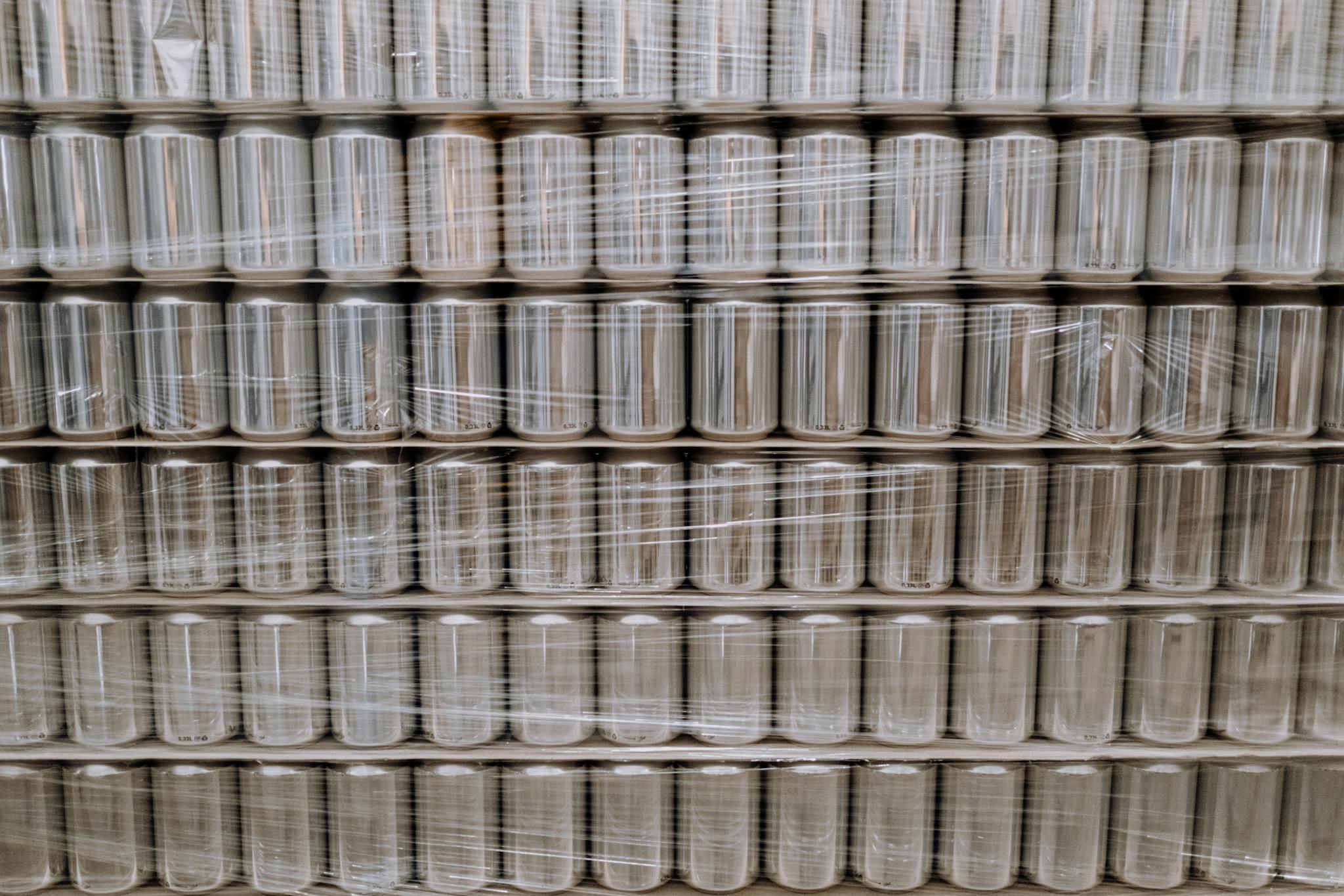 Pallets of empty cans wrapped in plastic film, ready for industrial use.